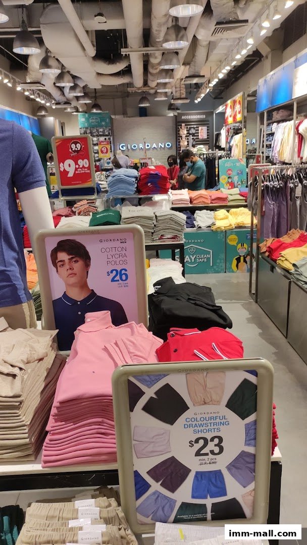 Interior view of a Giordano store showcasing folded polo shirts and shorts with promotional signage.