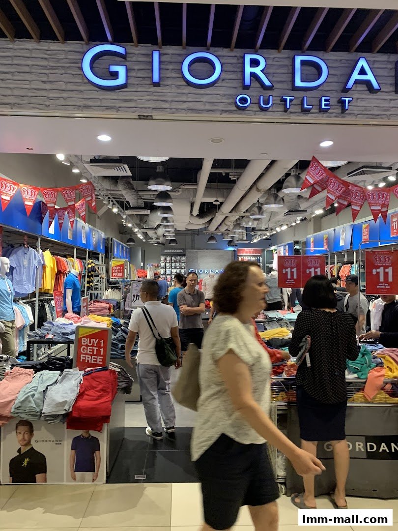 The entrance of a Giordano Outlet store with clothing displays and shoppers.