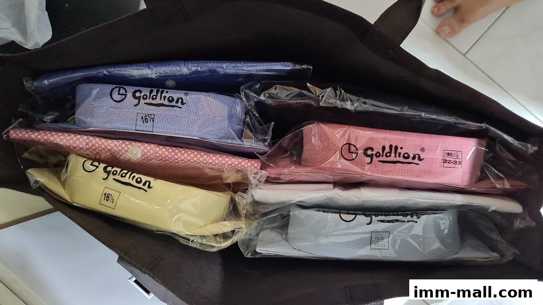 A dark tote bag filled with neatly folded and packaged Goldlion shirts in various colors.