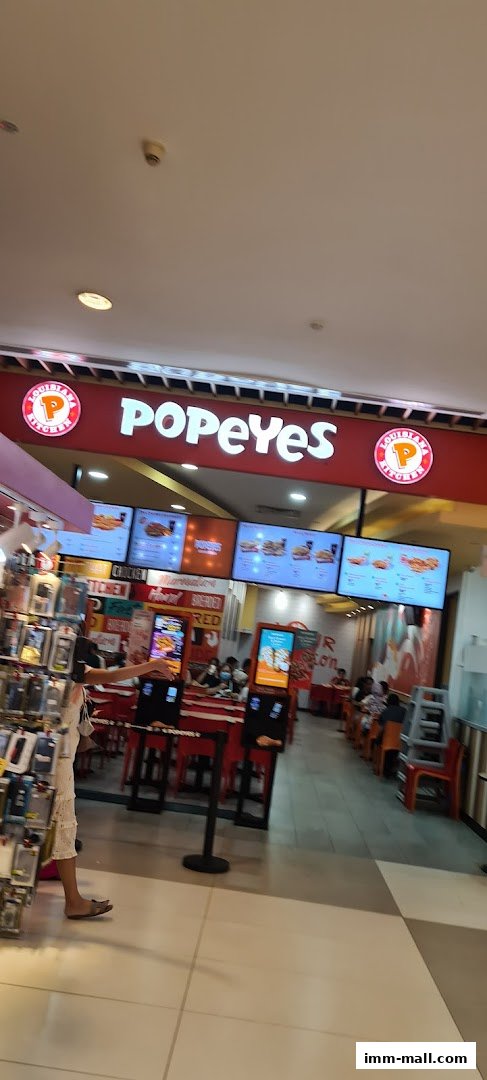 Interior view of a Popeyes restaurant with digital menus and seating areas.