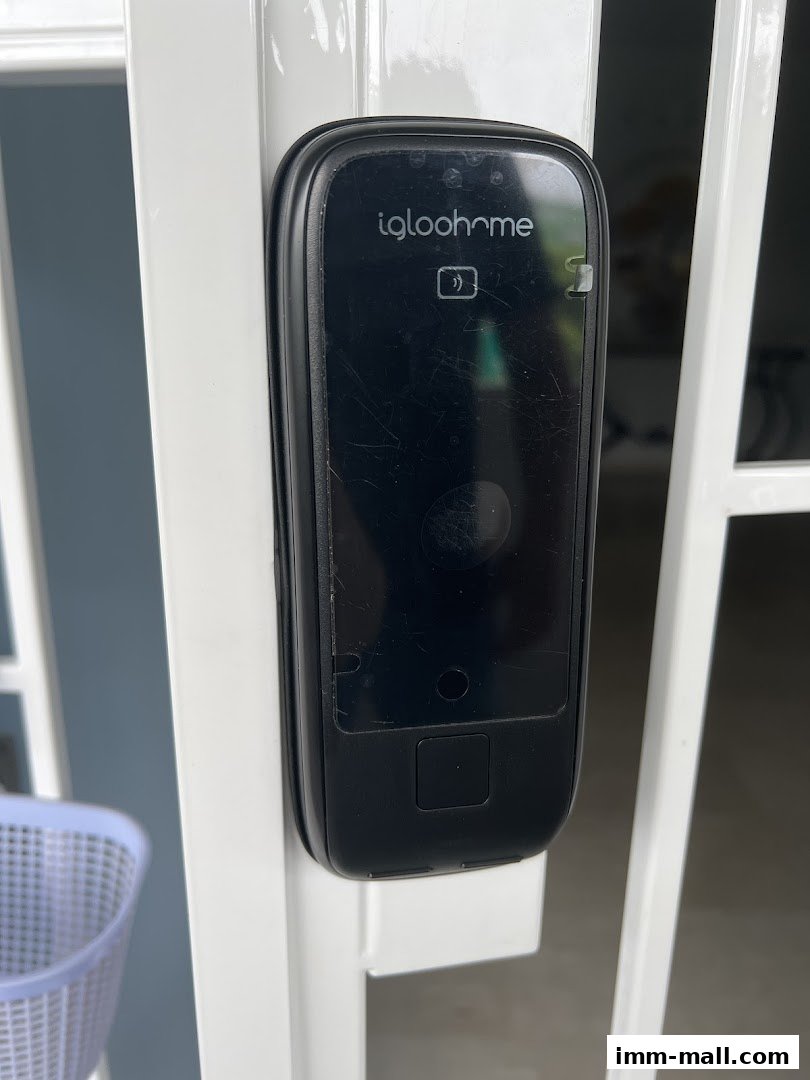 A close-up of a black Igloohome smart lock on a white gate.