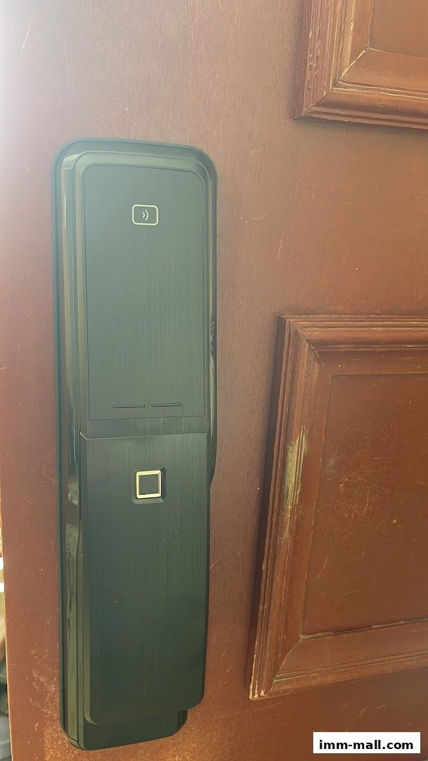 A modern black smart lock with fingerprint and card reader on a wooden door.