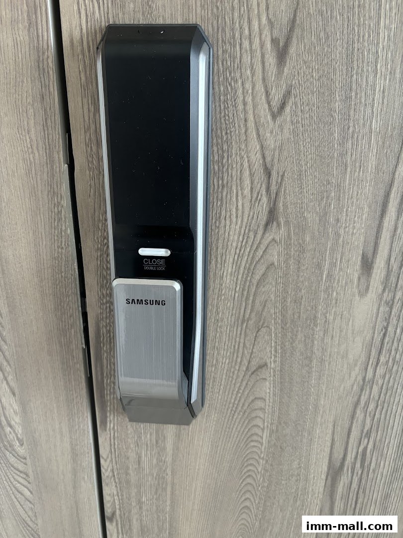 A close-up of a modern Samsung digital door lock on a wooden door.