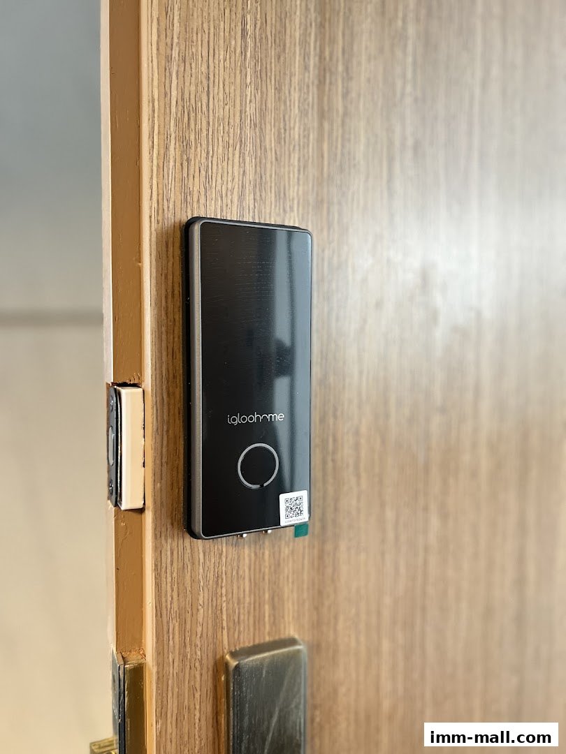 A close-up of a modern black smart lock with a QR code on a wooden door.