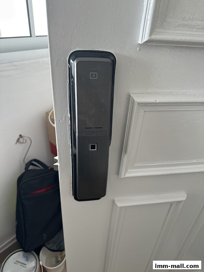 A modern digital door lock with a keypad and fingerprint scanner is installed on a white door.