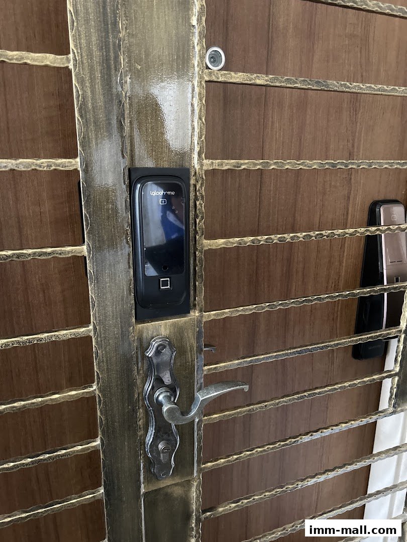 A close-up of a modern digital lock and handle on a metal and wood gate.