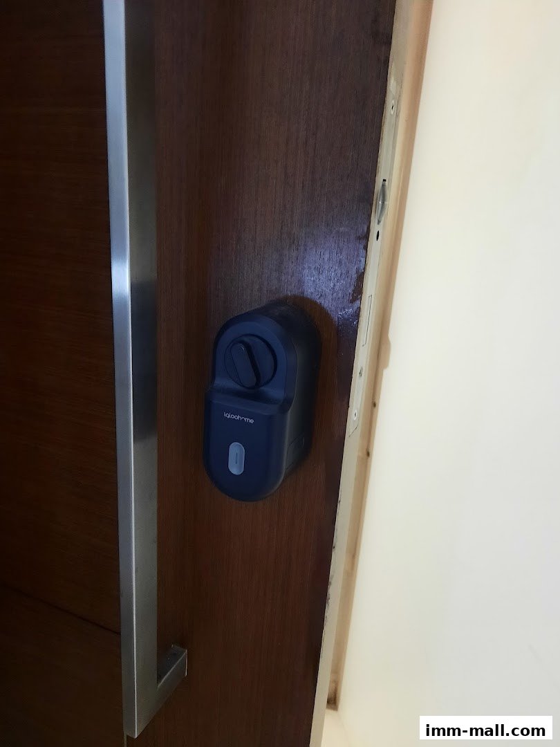 A close-up of a wooden door with a modern smart lock and a brushed metal handle.
