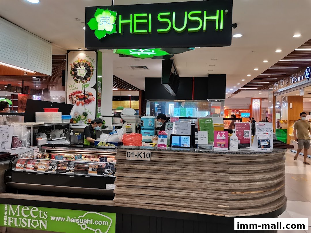 The Hei Sushi shop front with a display of sushi and staff preparing orders.