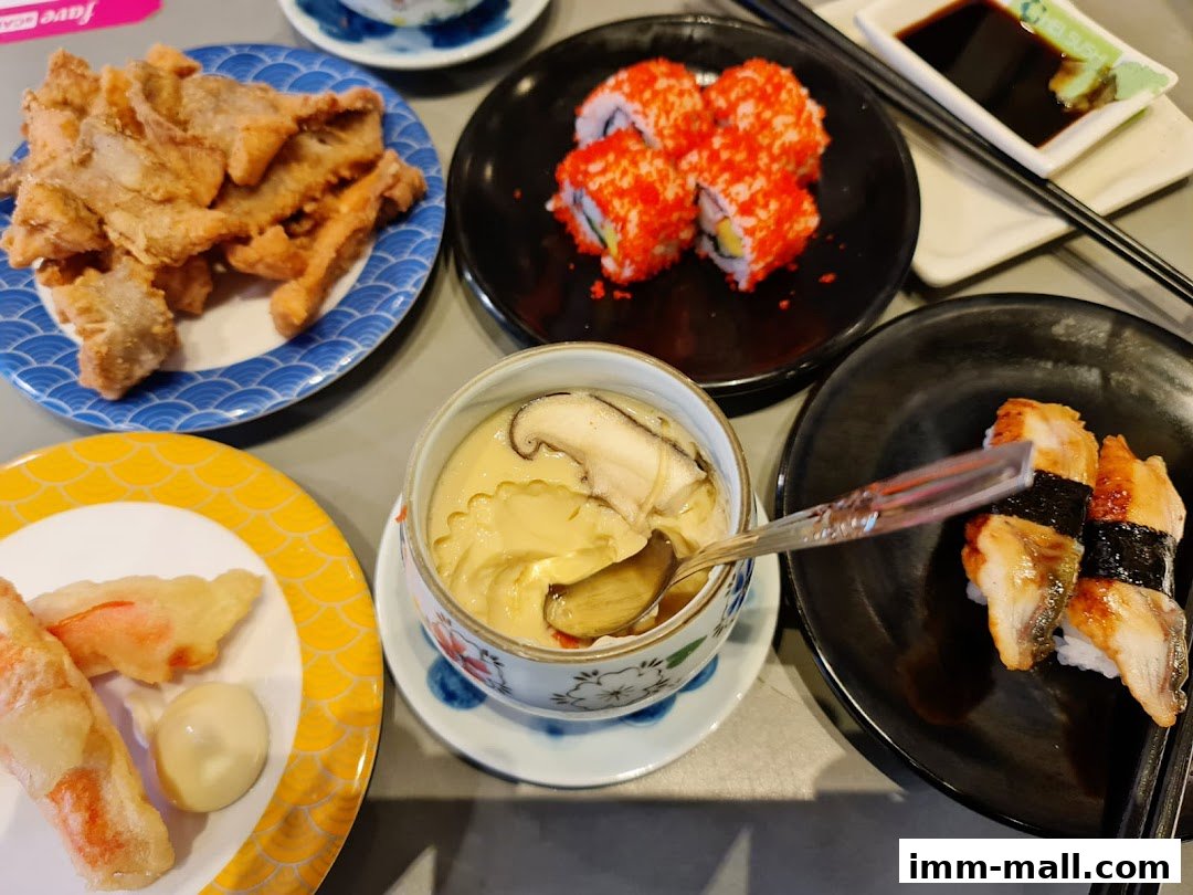 A variety of Japanese dishes including sushi, fried items, and chawanmushi are displayed on a table.