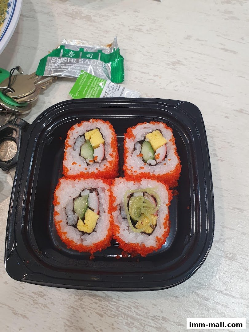 A black container holds four pieces of sushi with orange roe, cucumber, and egg.