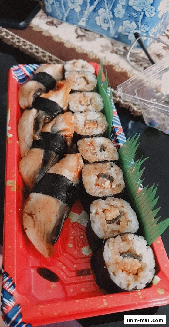 A red tray filled with assorted sushi pieces, including nigiri and maki rolls.