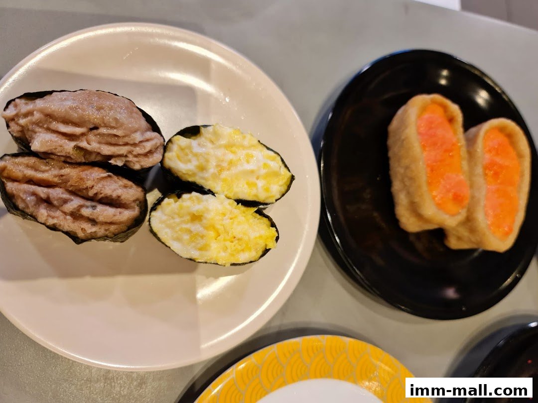 Close-up of sushi dishes on plates, featuring tuna and egg sushi, and inari sushi.