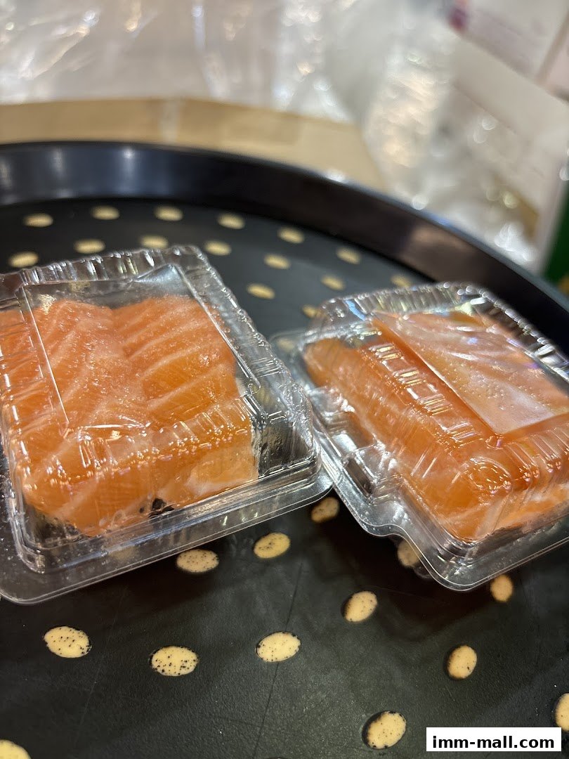 Two clear plastic containers filled with fresh salmon sashimi slices.