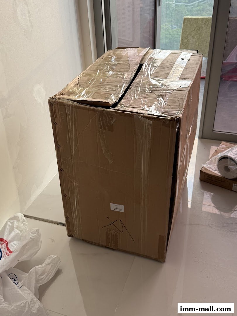 A large cardboard box with tape and plastic bags on a tiled floor.