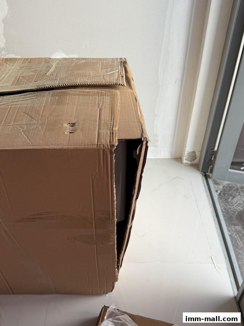 A damaged cardboard box with an item partially visible inside, near a doorway.