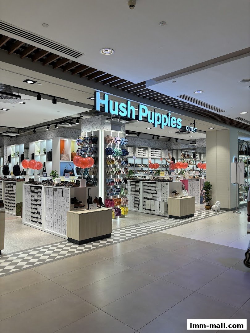 The Hush Puppies Outlet store displays a wide variety of footwear and bags, with colorful sandals prominently featured.