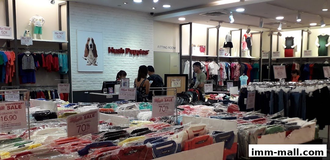 Interior view of a Hush Puppies store with clothing displays and sale signs.