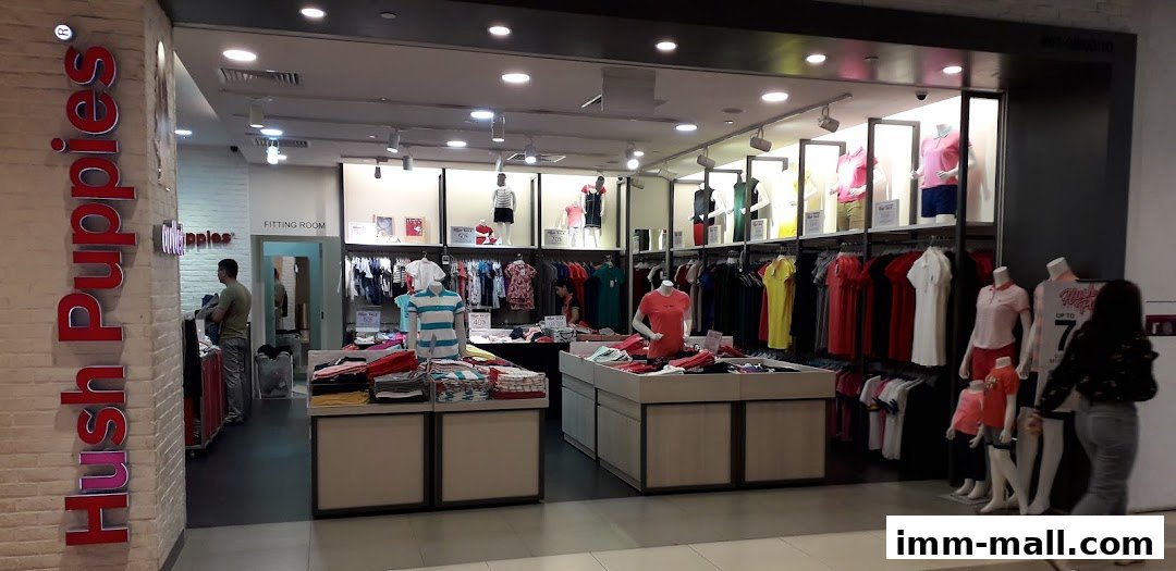 Interior view of a Hush Puppies store showcasing clothing and mannequins with sale signs.