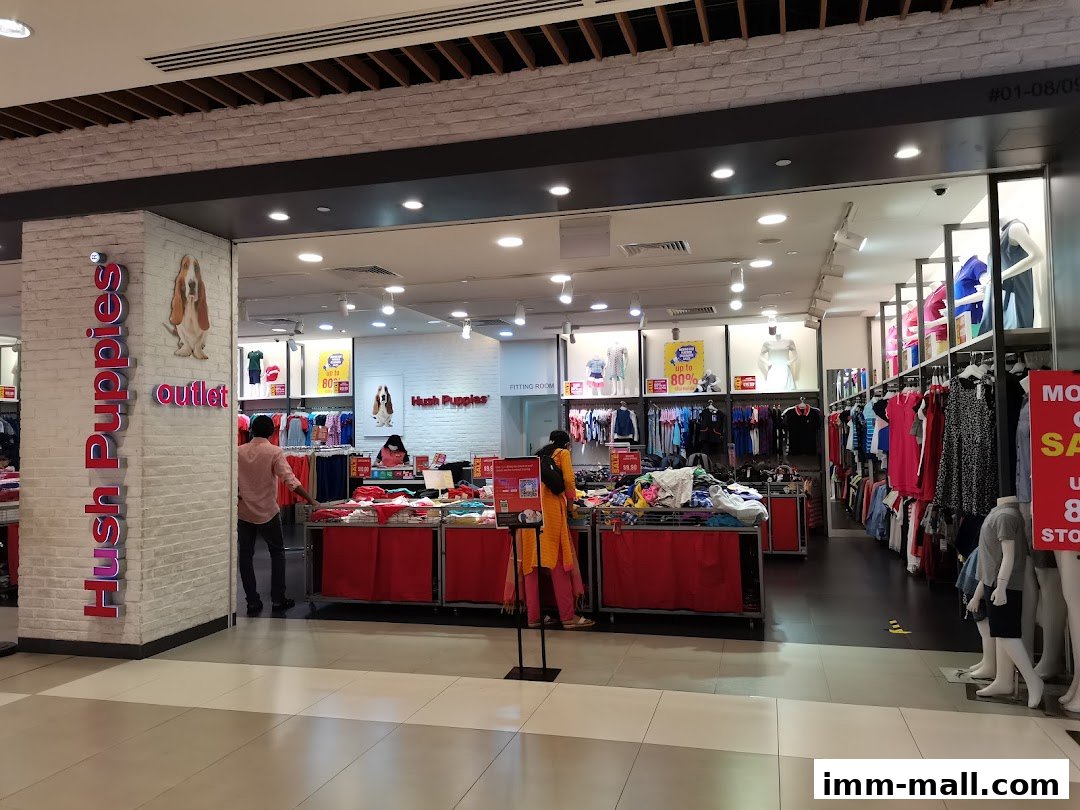 The entrance and interior of a Hush Puppies outlet store displaying clothing and bags.