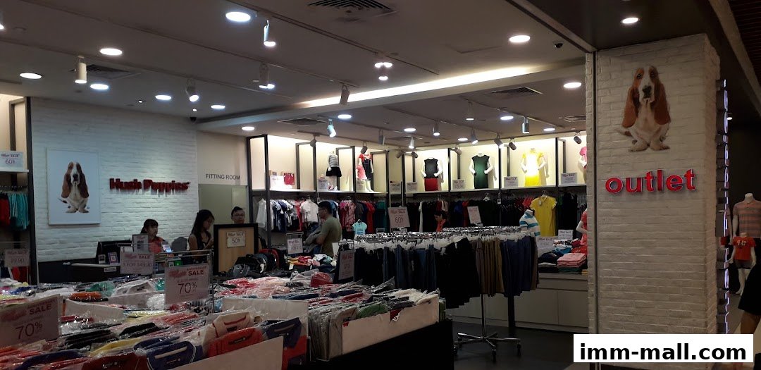 Interior view of Hush Puppies Outlet store with clothing displays and sale signs.
