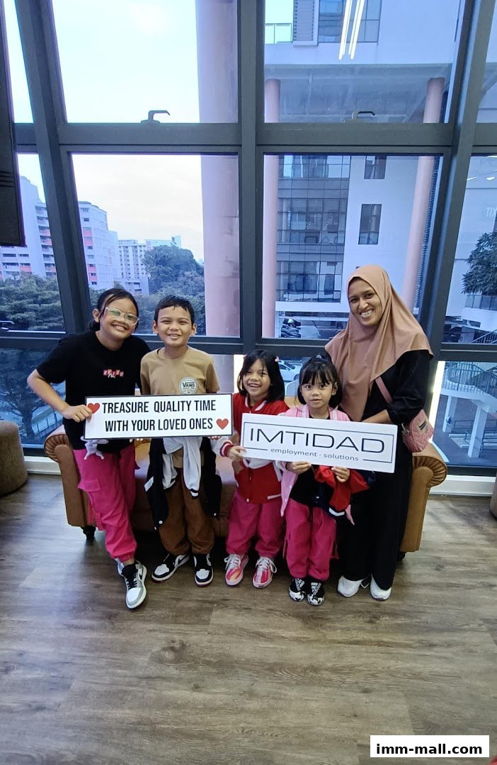 A family poses for a photo holding signs at the Imtidad Jurong IMM Branch.