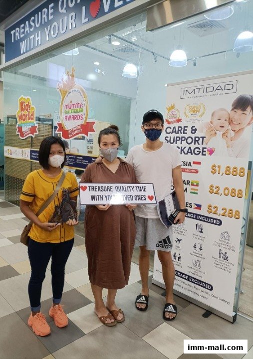 Three people posing in front of a shop with a banner advertising care and support packages.