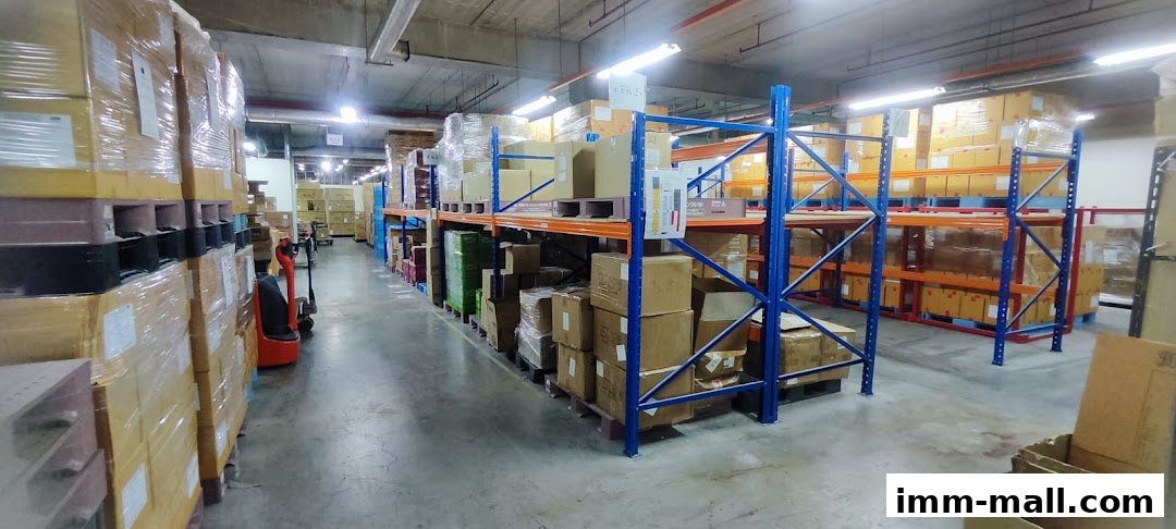 A warehouse interior with tall shelves stacked with boxes and pallets, and a forklift.