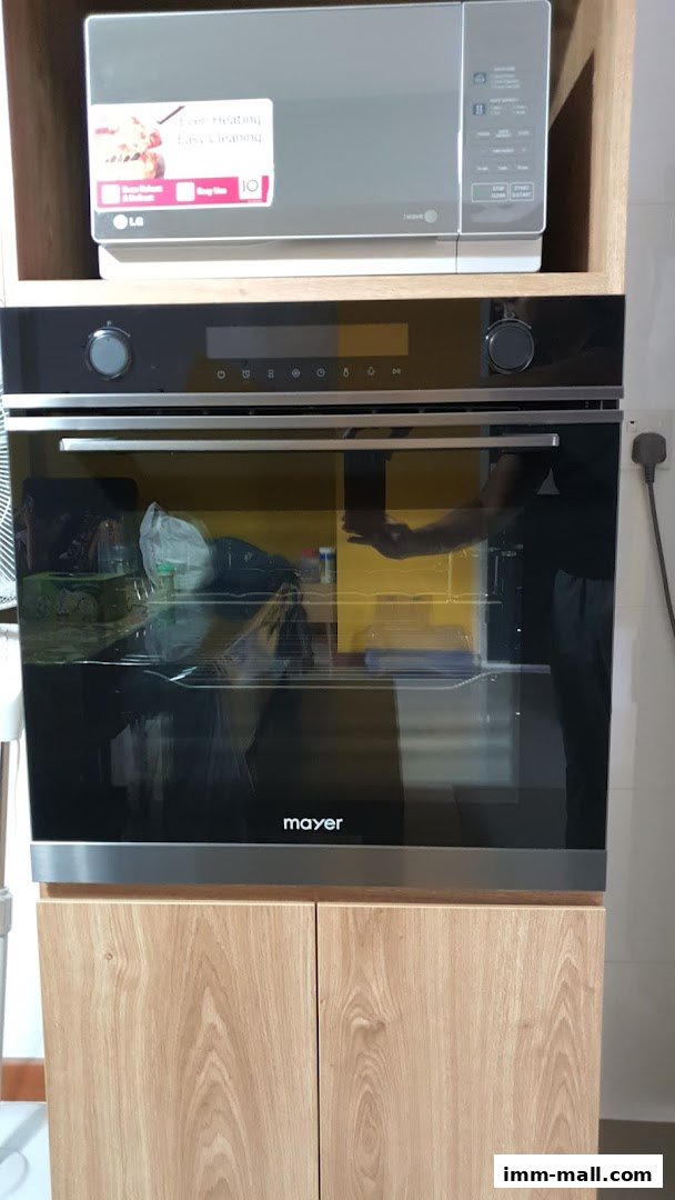 A built-in oven and microwave unit with wooden cabinetry.