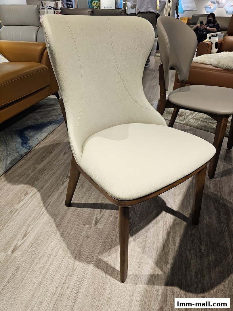 A close-up of a stylish cream-colored dining chair with wooden legs in a furniture store.