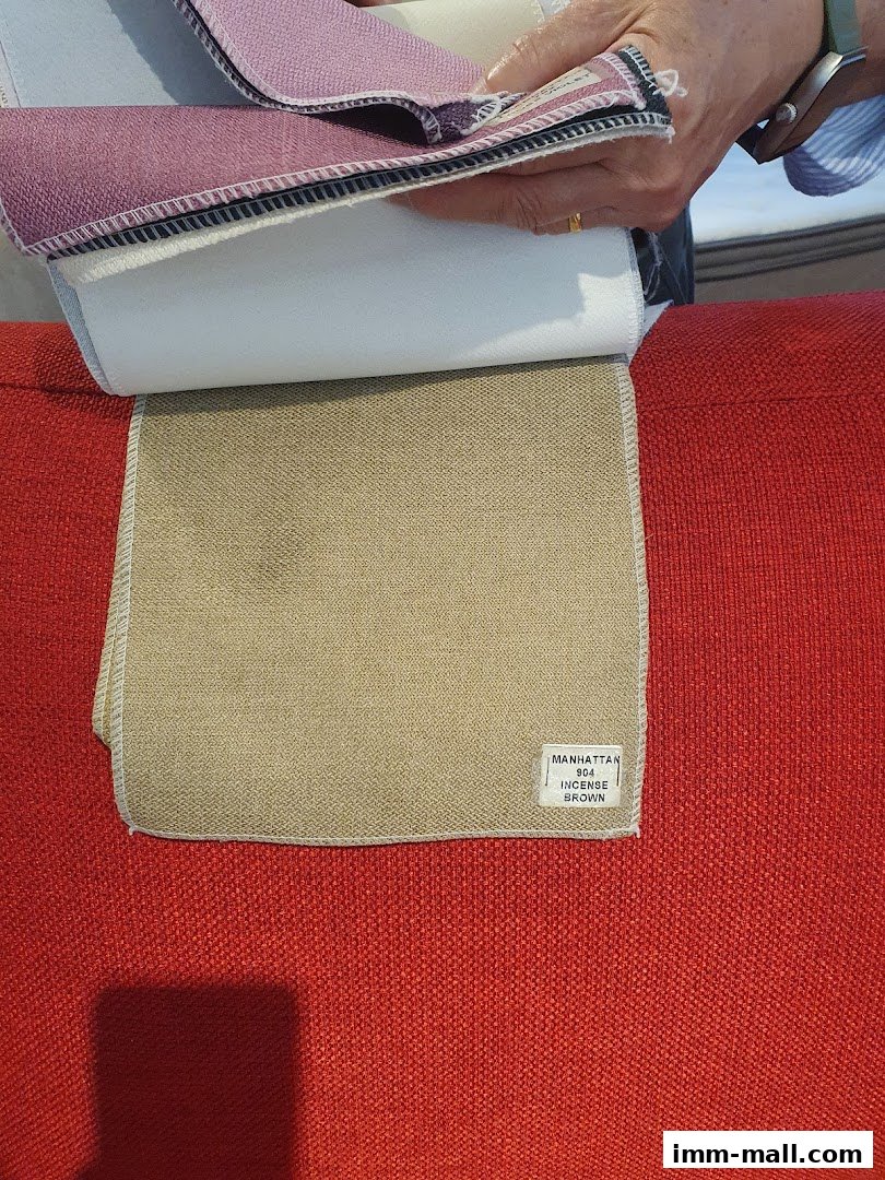 Hands holding fabric swatches over a red textured surface.