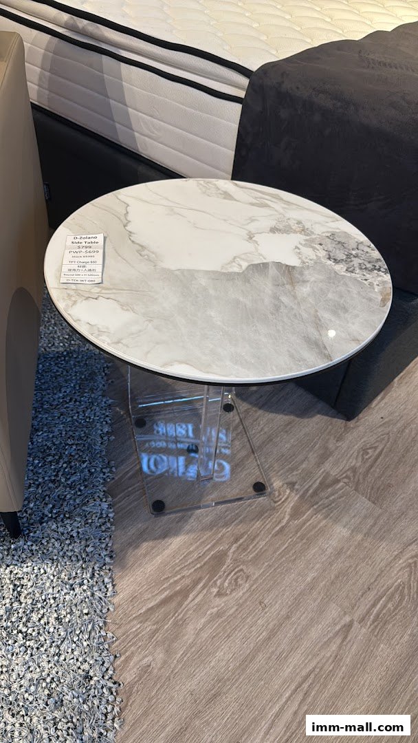 A stylish marble-top side table with a clear acrylic base displayed in a furniture store.