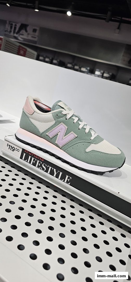 A New Balance women's lifestyle shoe in green and pink is displayed with a price tag.