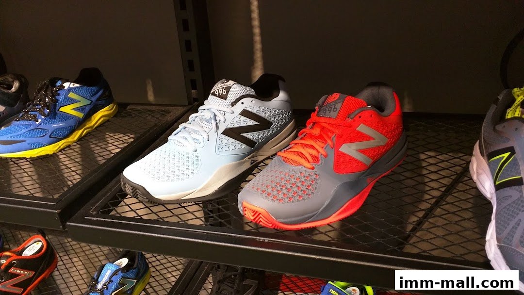 A display of New Balance athletic shoes in various colors on shelves.