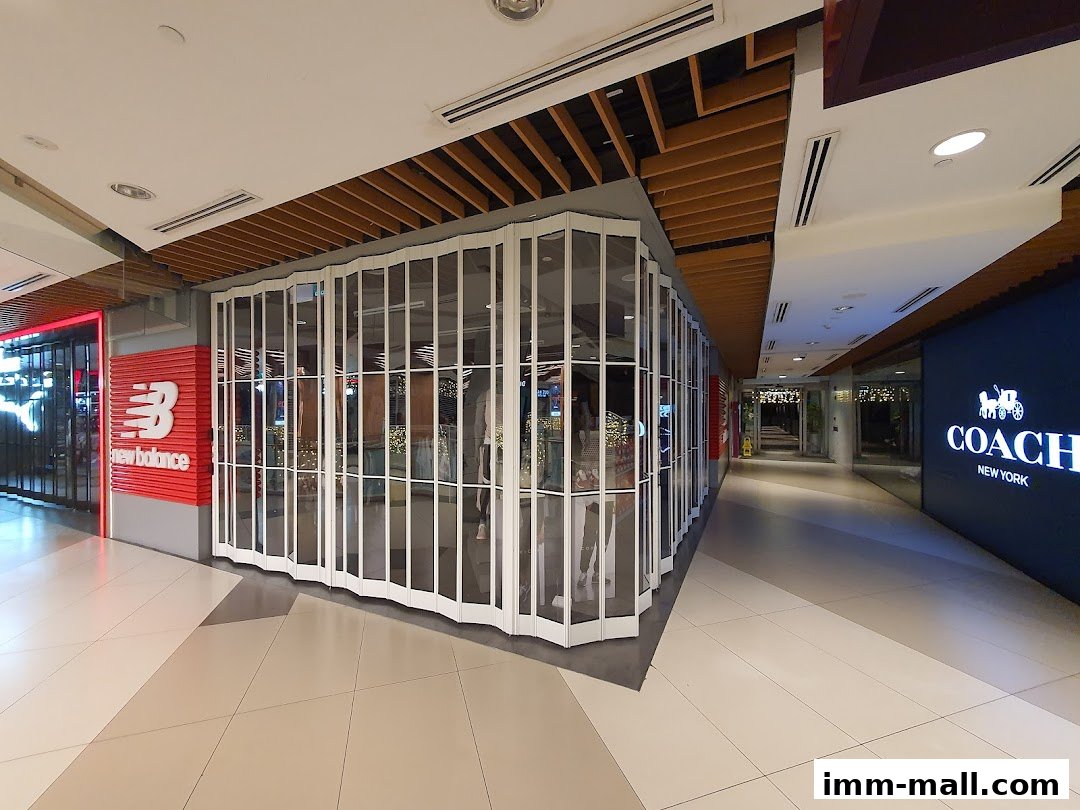 The New Balance Premium Factory Outlet shop front with its signature logo and a closed accordion-style gate.