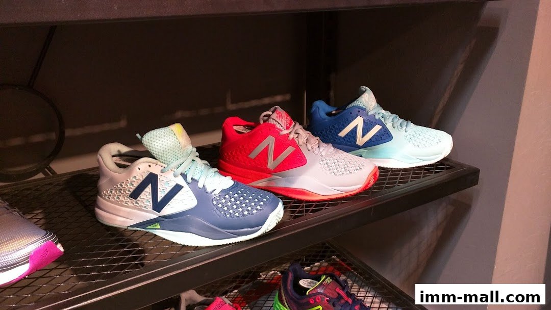 Three pairs of New Balance athletic shoes displayed on shelves in various colors.
