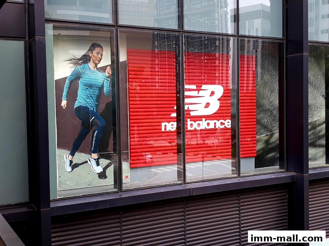 New Balance Factory Outlet storefront with a running advertisement and prominent logo.