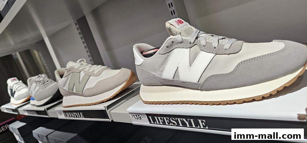 New Balance lifestyle sneakers displayed on shelves with price tags.