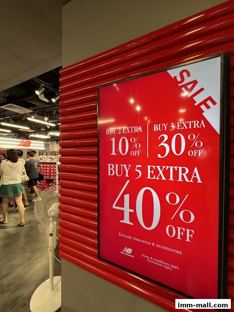 A New Balance Factory Outlet store with a large red sale sign advertising discounts.