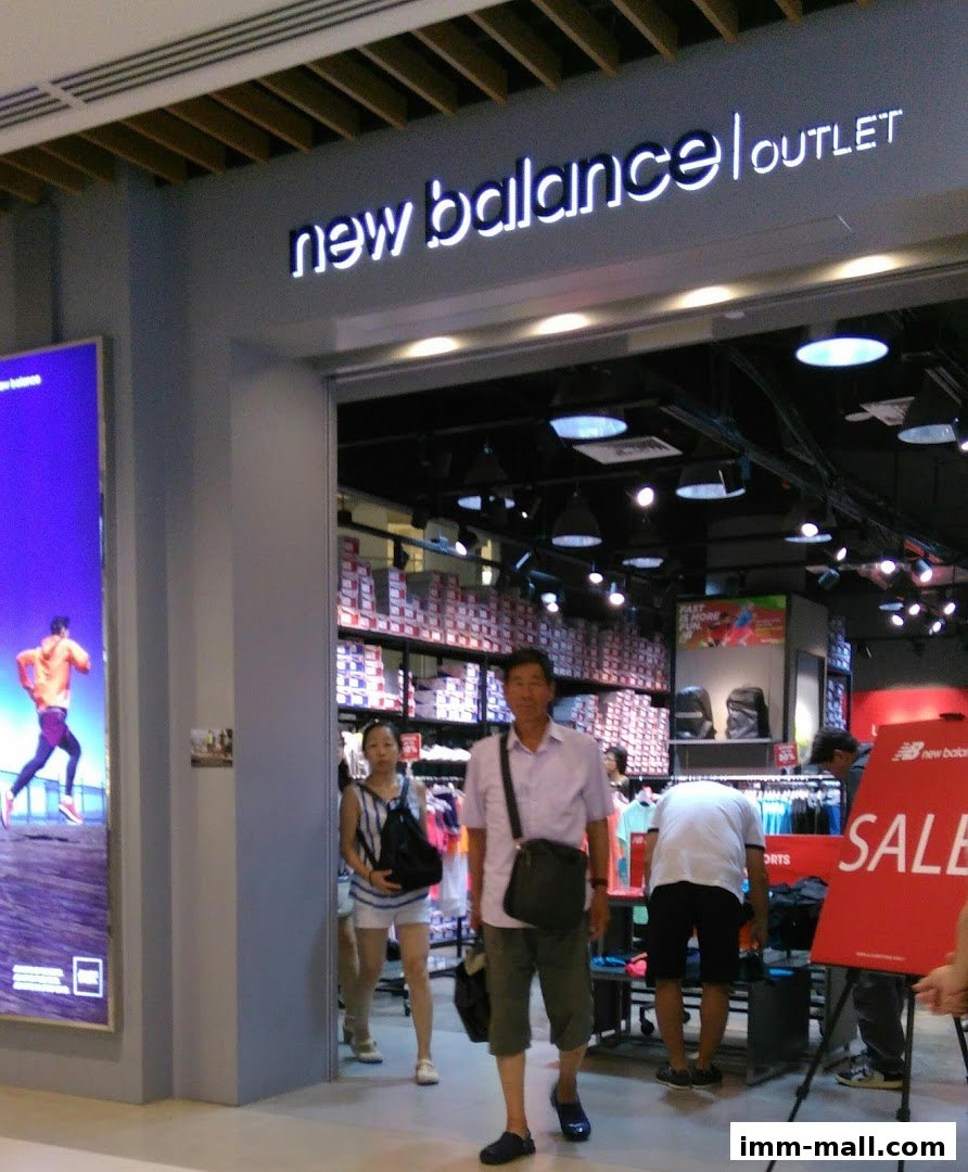 The entrance to a New Balance outlet store with people browsing inside.