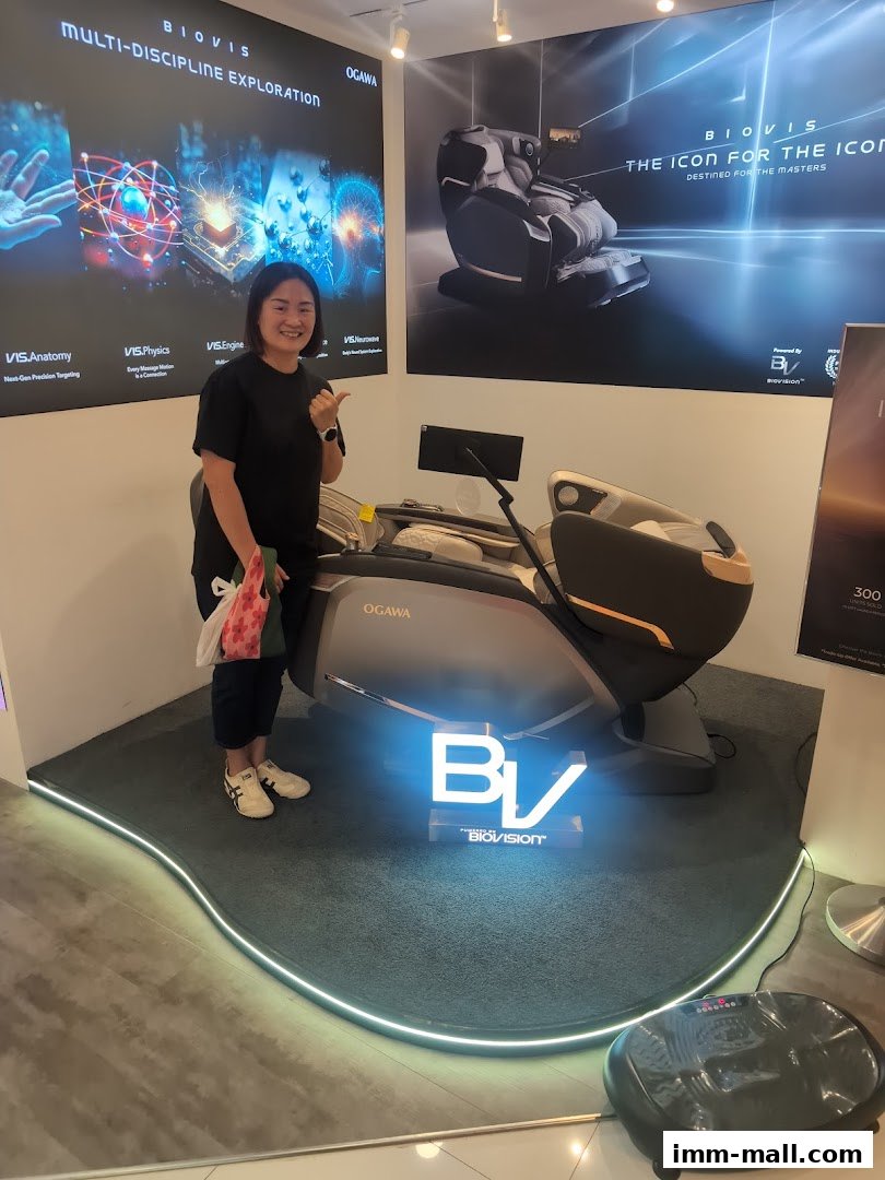 A woman gives a thumbs up next to a luxurious OGAWA massage chair.