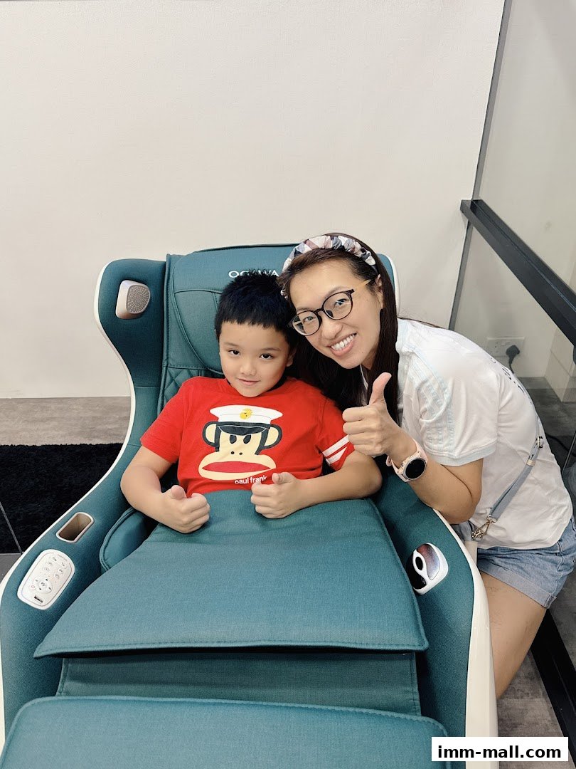 A woman and a child are smiling and giving thumbs up while sitting in a massage chair.
