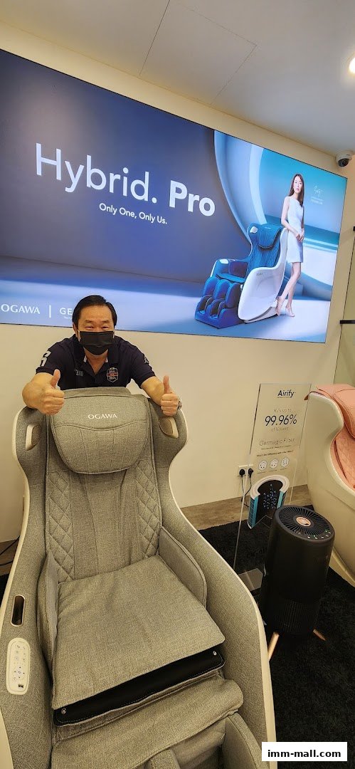 A man gives a thumbs up next to an OGAWA massage chair and an Airify air purifier.