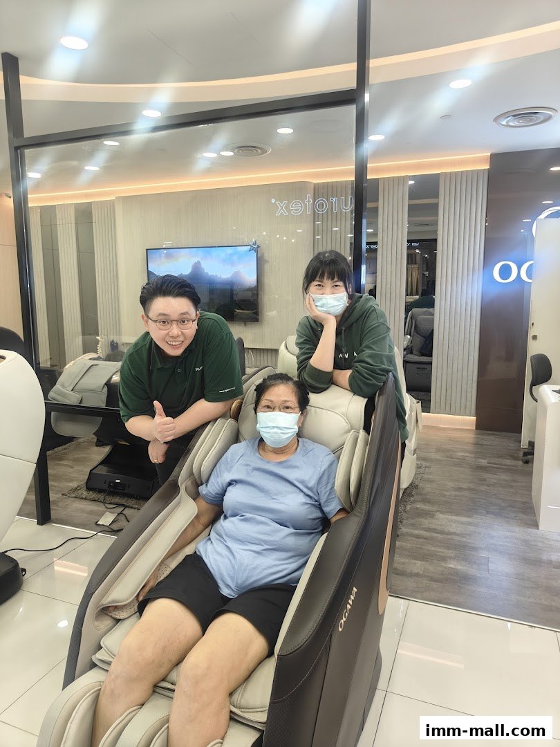 A woman sits in a massage chair with two staff members smiling behind her.