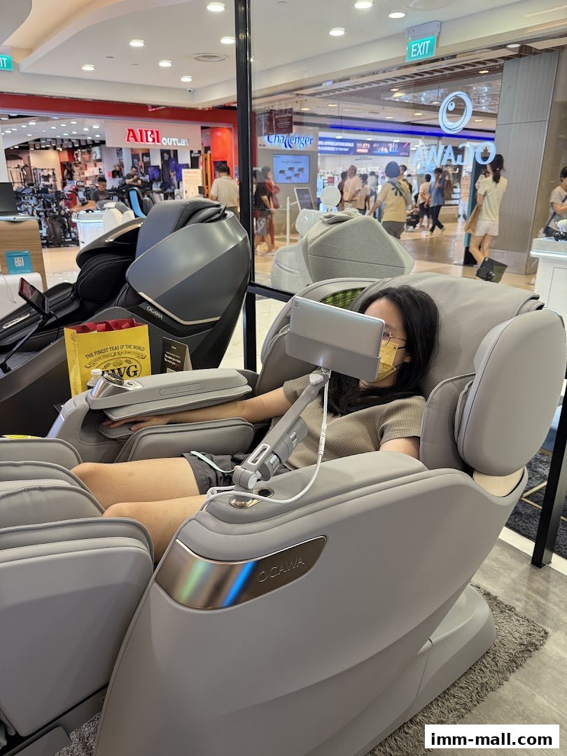 A person relaxing in an OGAWA massage chair in a shopping mall.