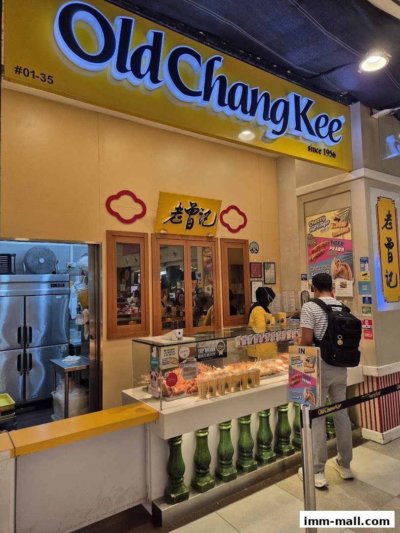 The Old Chang Kee shop front with a bright yellow sign and display of food items.