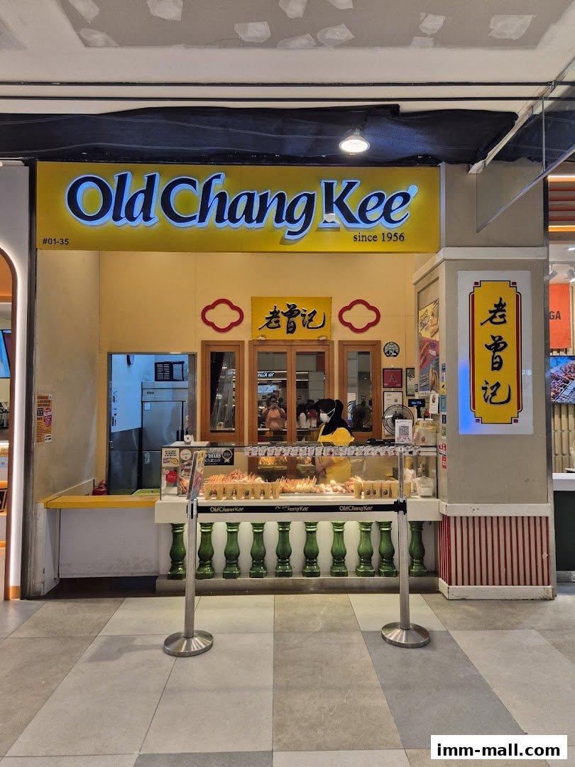 Old Chang Kee shop front with a display of food items and a staff member serving.