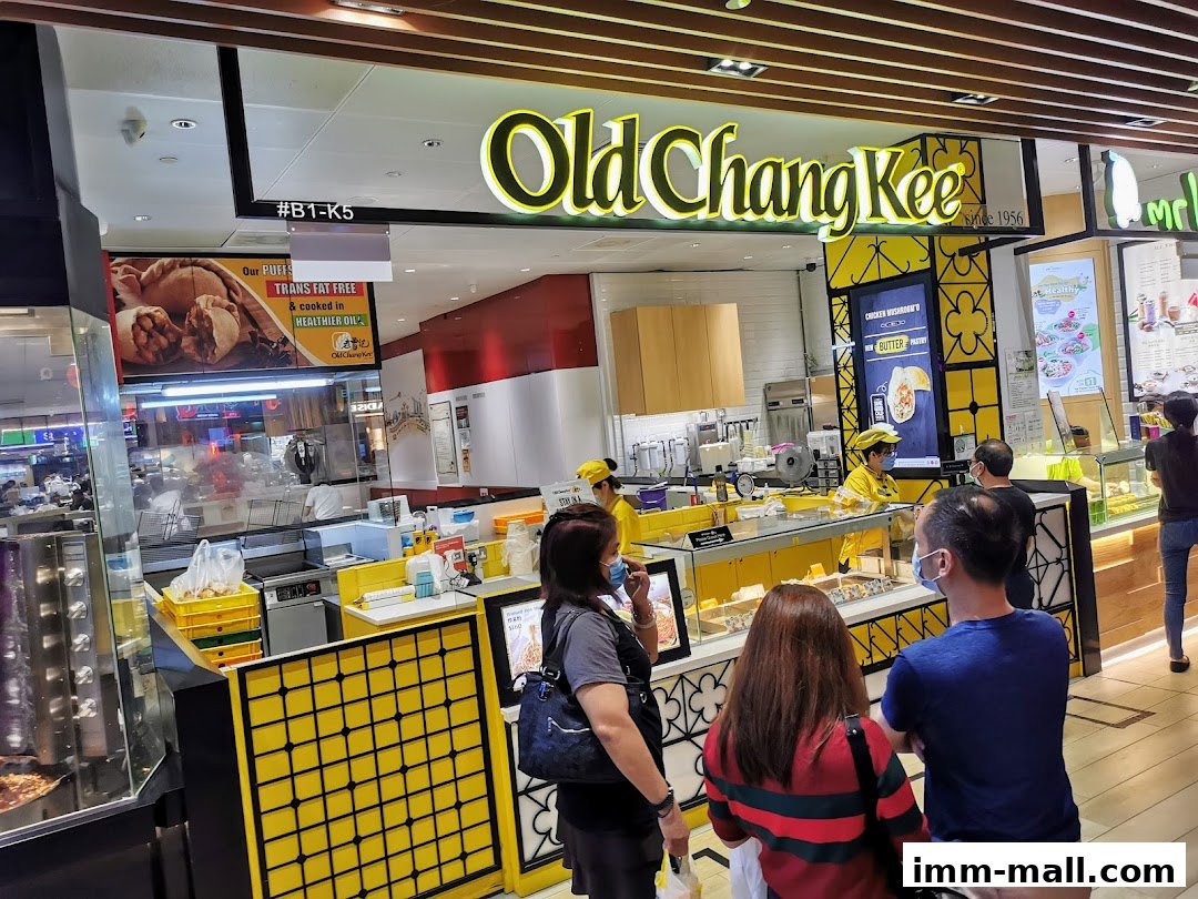 Customers queue at the Old Chang Kee food stall, with staff serving behind the counter.
