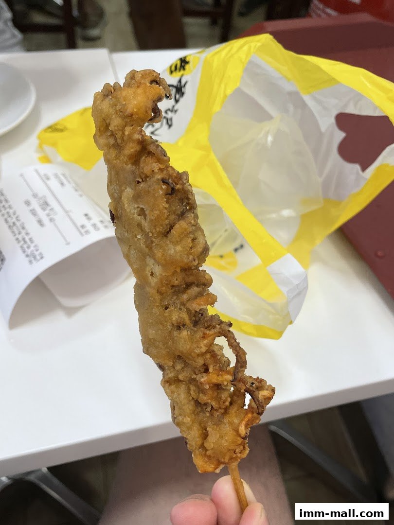 A person holds a crispy fried calamari skewer from Old Chang Kee.