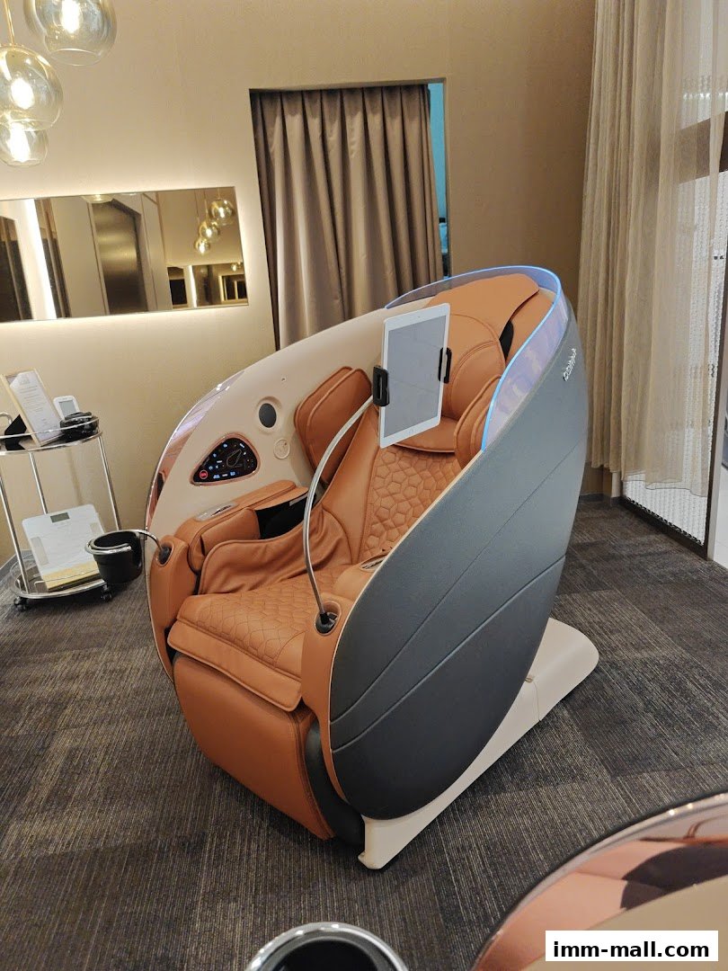 A luxurious brown massage chair with a tablet holder is displayed in a well-lit retail space.
