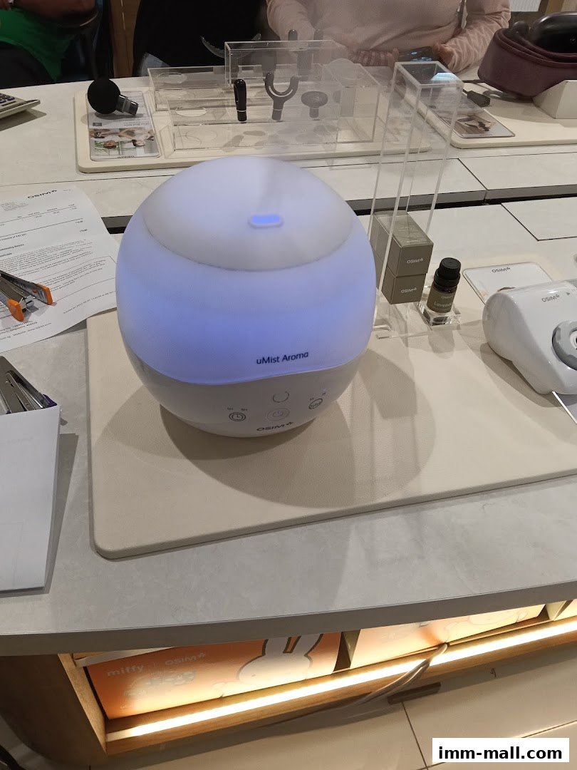 An OSIM uMist Aroma diffuser with blue light is displayed on a counter with other products.